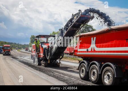 Straßenbau, Kaltfräsmaschine entfernt alte Asphaltschicht und füttert den LKW mit gefrästem Asphalt, Rehabilitation der Autobahn A3 dazwischen Stockfoto