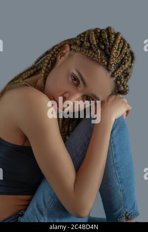 Enttäuschte junge afroamerikanische Frau, die ihren Kopf auf das Knie setzt Stockfoto