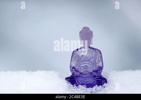 Lila Kunststoff buddha Statue im Schnee Stockfoto