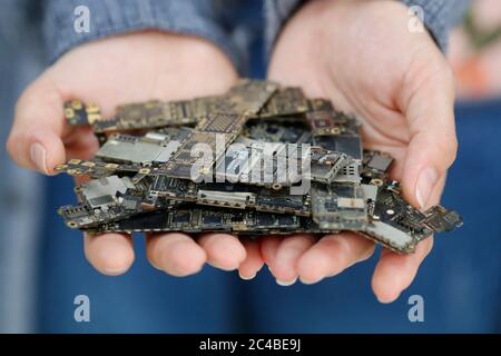 Elektronische Elemente einer alten gebrauchten Leiterplatte in den Händen Stockfoto