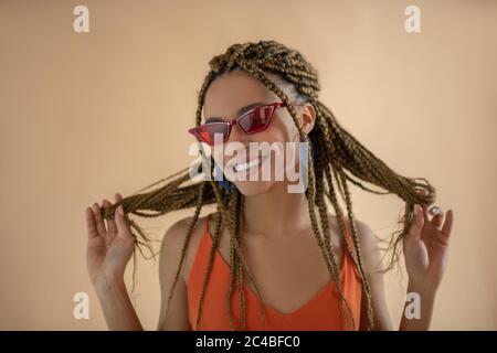 Lächelnde junge Afroamerikanerin, die mit ihren Dreadlocks spielt Stockfoto