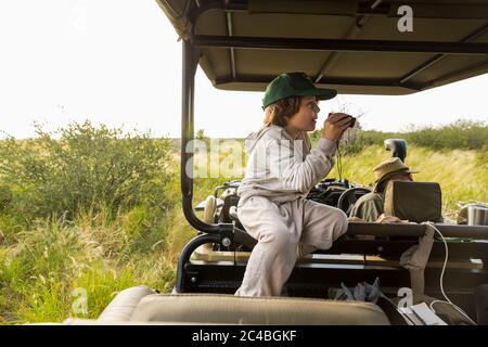 6 Jahre alter Junge mit Fernglas im Safarizehikel, Botswana Stockfoto