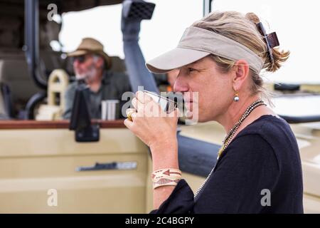 Erwachsene Frau schlürft Kaffee auf Safari, Nxai Pan, Botswana Stockfoto