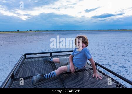 6 Jahre alter Junge und Guide auf dem Safari-Fahrzeug, Nxai Pan, Botswana Stockfoto