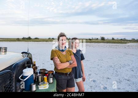 Mutter und Tochter auf Safari stehen bei Sonnenuntergang an einem Jeep Stockfoto