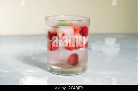 Hausgemachte gefrorene Erdbeer-Limonade mit Eiswürfeln und einem Zweig Minze auf grauem Hintergrund. Ein erfrischendes Sommergetränk. Speicherplatz kopieren. Stockfoto