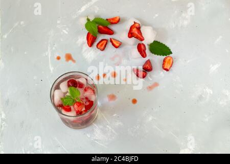Hausgemachte Erdbeerlimonade mit Eis und einem Zweig Minze auf grauem Hintergrund. Erfrischendes Getränk. Speicherplatz kopieren. Stockfoto