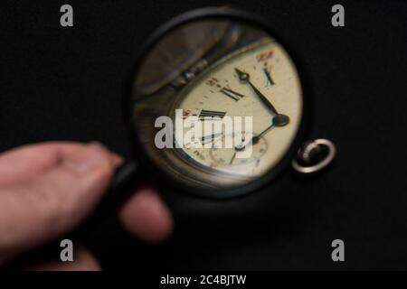 Lupe mit einer alten Taschenuhr auf schwarzem Hintergrund Stockfoto