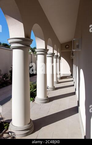 Veranda eines italienischen Wohnhauses mit Säulen und Bögen aus Zement und quadratischen Steinfliesen, Hinterhof an einem sonnigen Sommertag niemand. Stockfoto