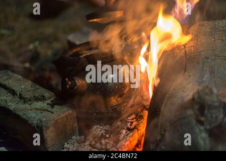 Der Wasserkocher wird nachts an einem hellen Feuer im Freien erhitzt Stockfoto