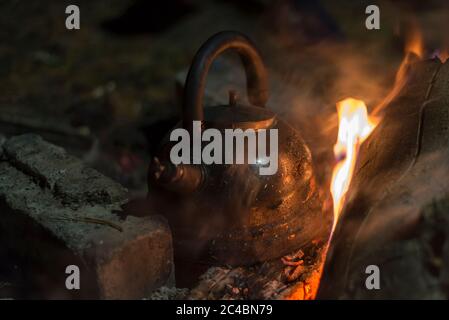 Der Wasserkocher wird nachts an einem hellen Feuer im Freien erhitzt Stockfoto