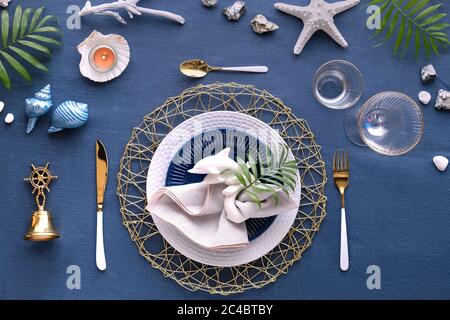 Columbus Day oder Sommergeburtstag Lunch Tisch, blau weiß, grün. Flache, moderne nautische Tischgestaltung mit Meeresdeko auf klassischem blauem lin Stockfoto