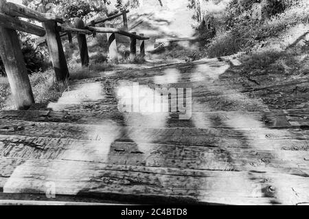 Schwarz-weiße Hochwinkelaufnahme von verwitterten Holztreppen im Freien mit dramatischen Sonnenlichtschatten Stockfoto