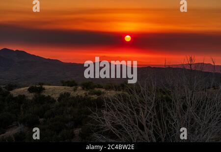 Rauch vom Bighorn Feuer, der in den Santa Catalina Bergen nördlich von Tucson brennt, filtert die Sonne kurz nach der Morgendämmerung, wie man sie von den Grasländern aus sieht Stockfoto