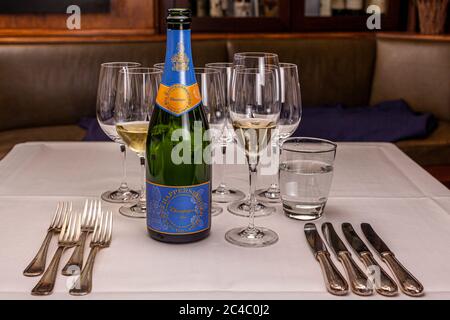 Eine Flasche Champagne Happersberger steht vor gefüllten Champagner- und Weingläsern auf einem gedeckten Tisch im Hotel und Restaurant Kronenschlösschen in Hattenheim, Eltville am Rhein, Hessen, Deutschland. Der Champagner ist der Aperitif beim Galadinner des Zwei-Sterne-Kochs Erik van Loo (Restaurant Parkheuvel, Rotterdam) am 24. Februar 2017. Anlass ist das 21. Rheingau Gourmet & Wein Festival. Vier Gabeln und vier Messer liegen bereit für das mehrgängige Menü. Stockfoto