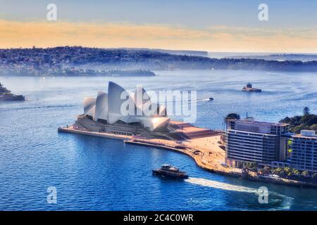 Sydney, Autralia - 20. Juni 2020: Sydney Opera House am Hafen von Sydney mit Passagierfähren aus der Höhe der Circular Quay Towers. Stockfoto