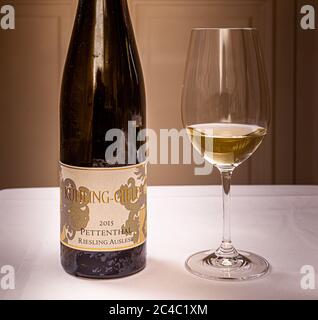 Eine Flasche 2015 Pettenthal Riesling Auslese vom Weingut Kühling-Gillot steht neben einem gefüllten Glas im Hotel und Restaurant Kronenschlösschen in Hattenheim, Eltville am Rhein, Hessen, Deutschland. Die Auslese begleitet das Dessert beim Galadinner des mit einem Michelin-Stern ausgezeichneten Koch Nick Bril am 26. Februar 2017, Teil des 21. Rheingau Gourmet & Wein Festivals: Schokolade, Rum, Zitrone und Kokosnuss. Das Pettenthal-Lage liegt nahe Nierstein am Roten Hang (roter Hang). Carolin Spanier-Gillot, 'Weinbauerin des Jahres 2015', präsentiert die Weine ihres Weinguts Kühling-Gillot in Bodenheim, Rheinhessen. Stockfoto