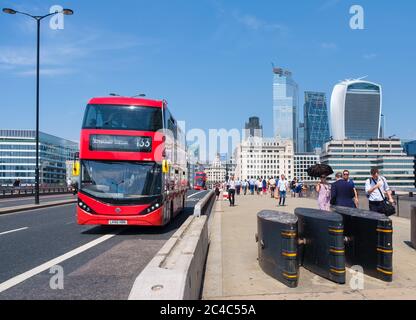 Typische Doppeldeckerbusse auf der London Bridge mit Blick auf die City of London an einem sonnigen Sommertag Stockfoto