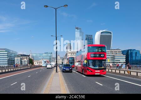 Typische Doppeldeckerbusse auf der London Bridge mit Blick auf die City of London an einem sonnigen Sommertag Stockfoto