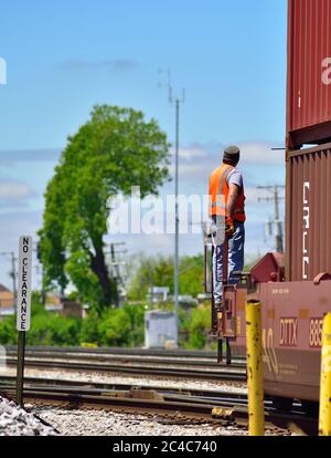 Franklin Park, Illinois, USA. Ein Zugbesatzungsmitglied, das am Ende einer Reihe von Autos fährt, die auf einer Yard Lead-Strecke geschaltet werden. Stockfoto