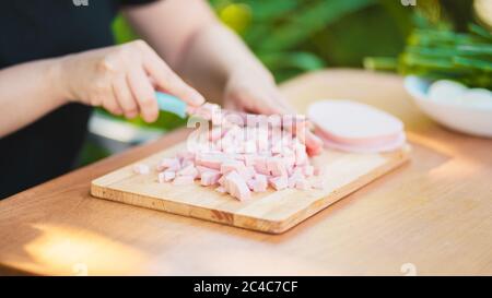 Junge Frau schneiden Wurst auf Holzbrett im Freien. Frauenhänden schneiden Wurstwaren mit Messer auf Schneidebrett. Stockfoto