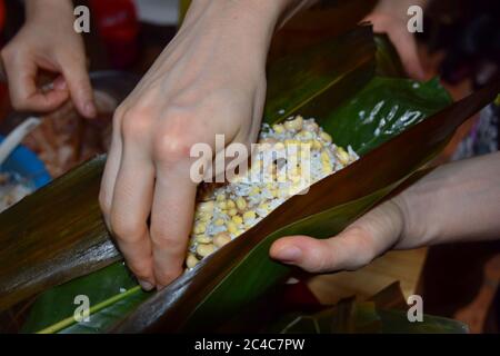 Zongzi, ein traditionelles chinesisches Reisgericht, das aus klejeweidem Reis besteht, der mit verschiedenen Füllungen gefüllt und in Bambusblätter eingewickelt ist. Stockfoto