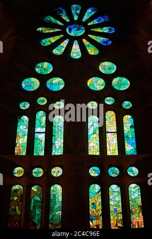 Auf der einen Seite spiegeln die Buntglasfenster der Sagrada Familia kühle Morgenfarben in Blau und Grün wider Stockfoto