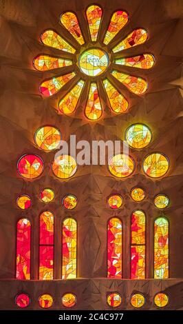 Auf der einen Seite spiegeln die Buntglasfenster der Sagrada Familia die untergehende Sonne wider, mit warmen Rot-, Orangen- und Gelbtönen; auf der anderen Seite kühlen Morgenfarben Stockfoto