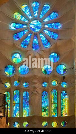 Auf der einen Seite spiegeln die Buntglasfenster der Sagrada Familia kühle Morgenfarben in Grün und Blau wider Stockfoto