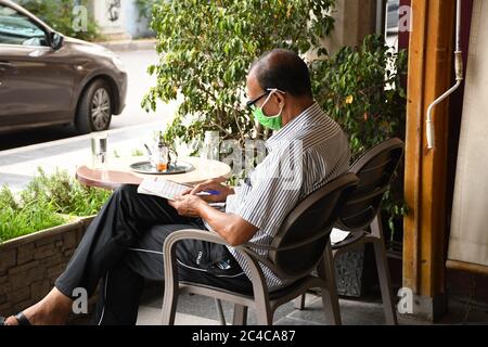 Rabat, Marokko. Juni 2020. Ein Mann mit Gesichtsmaske spielt Wortpuzzle in einem Café in Rabat, Marokko, 25. Juni 2020. Marokko begann am Donnerstag, die Pandemie-Beschränkungen zu lockern, indem es den Menschen erlaubte, innerhalb des Landes zu reisen und die Cafés und Restaurants wieder zu öffnen. Quelle: Chadi/Xinhua/Alamy Live News Stockfoto