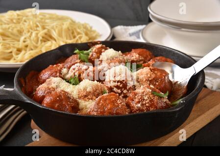 Spaghetti-Sauce mit Fleischbällchen in einer gusseisernen Pfanne mit einem Teller Pasta Stockfoto