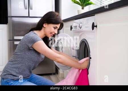 Frau Mit Waschmaschine Reinigung Kleidung In Der Küche Stockfoto