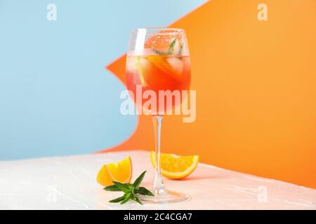 Komposition mit aperol Spritz Cocktail auf farbigem Hintergrund. Sommergetränk Stockfoto