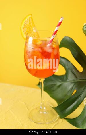 Aperol Spritz Cocktail und Palmblatt auf gelbem Hintergrund. Sommergetränk Stockfoto