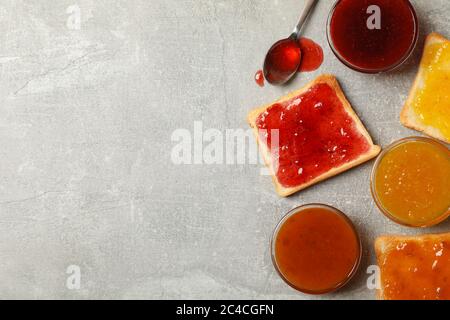 Schalen und Toasts mit Marmelade auf grauem Hintergrund, Draufsicht Stockfoto