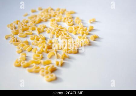 Rohe Nudelbuchstaben des Alphabets gemischt in Haufen auf weißem Hintergrund Stockfoto