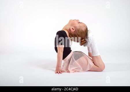 Kleines Mädchen macht Stretching und Gymnastik-Übungen auf weißem Hintergrund Stockfoto