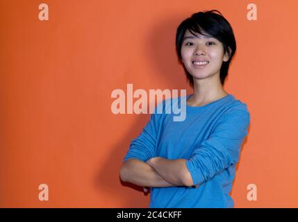 Schöner chinesischer junger Erwachsener mit blauem Hemd isoliert auf orangefarbenem Hintergrund Stockfoto