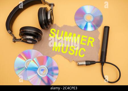 Kopfhörer, Mikrofon und Musik-Discs auf gelbem Hintergrund. Inschrift SOMMERMUSIK. Stockfoto