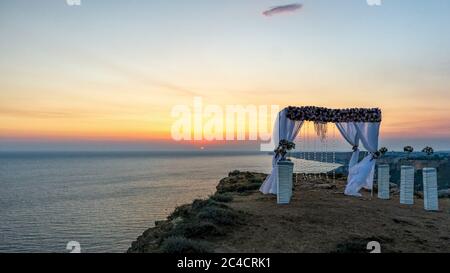 Hochzeitsbogen mit Blumen auf einem Hintergrund von Felsen und Meer bei Sonnenuntergang dekoriert. Die Hochzeit in Krim, das Kap Fiolent Stockfoto