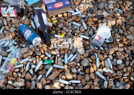 Brighton UK 26. Juni 2020 - Nitroxid-Gasbehälter zwischen Müllhaufen am Brighton Strand und am Meer heute Morgen, die von den Massen von Besuchern gestern zurückgelassen wurden, der bisher heißeste Tag des Jahres war : Credit Simon Dack / Alamy Live News Stockfoto