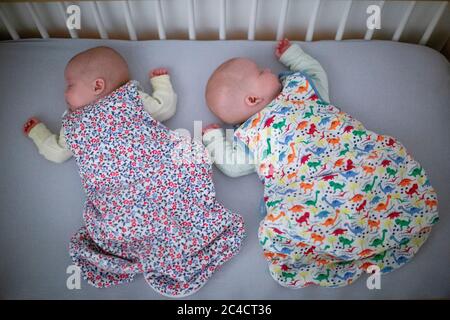 Neugeborenes Baby Jungen und Mädchen Zwillinge schlafen in einem Kinderbett in bunten Schlafsäcken. Foto von Sam Mellish Stockfoto