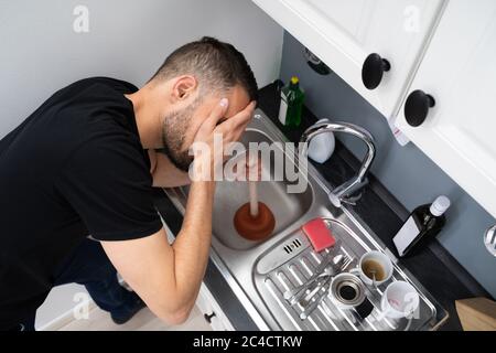 Reinigen Von Verstopften Abflussverstopfungen Im Küchenwaschbecken Mit Stößel Stockfoto