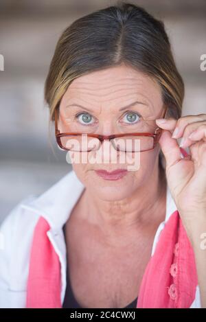 Potrait smart attraktive reife Geschäftsfrau mit Brille und ernster Ausdruck, verschwommener Hintergrund. Stockfoto