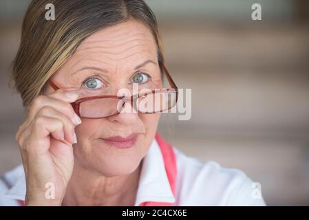 Potrait smart attraktive reife Geschäftsfrau mit Brille und freundlich neugierig Ausdruck, verschwommen Hintergrund. Stockfoto
