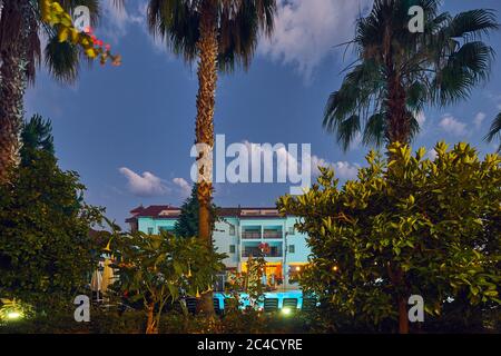 Pool im Hotel nachts, Türkei. Palmen, tropische Pflanzen, Hotelgebäude, Abendhimmel. Stockfoto