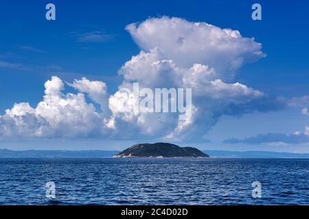 Landschaft mit dem Meer, Insel und schönen Wolken am blauen Himmel. Insel Kelifos, Ägäis, Chalkidiki, Griechenland, Blick vom Meer. Stockfoto