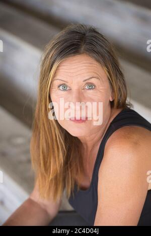 Portrait Attraktive reife Frau allein sitzend und einsam, traurig nachdenklicher Gesichtsausdruck, nach oben schauen, verschwommener Hintergrund. Stockfoto