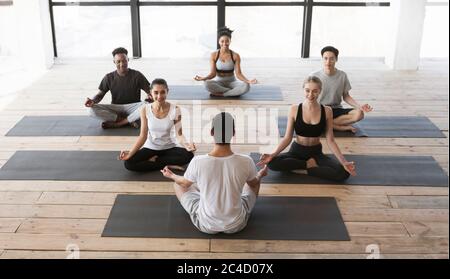 Gruppe junger Leute, die Yoga-Kurs mit Trainer im Studio Stockfoto