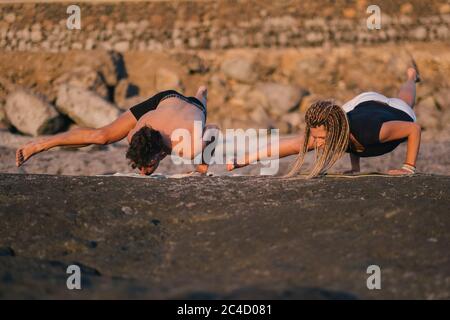 Fitness, Sport und Lifestyle-Konzept - Paar macht Yoga-Übungen am Strand Stockfoto